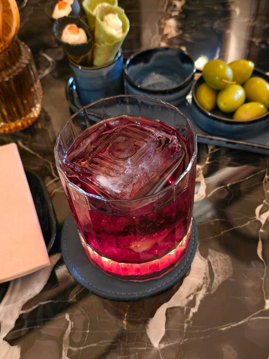 Classic Negroni cocktail with large ice cube and aperitivo snacks